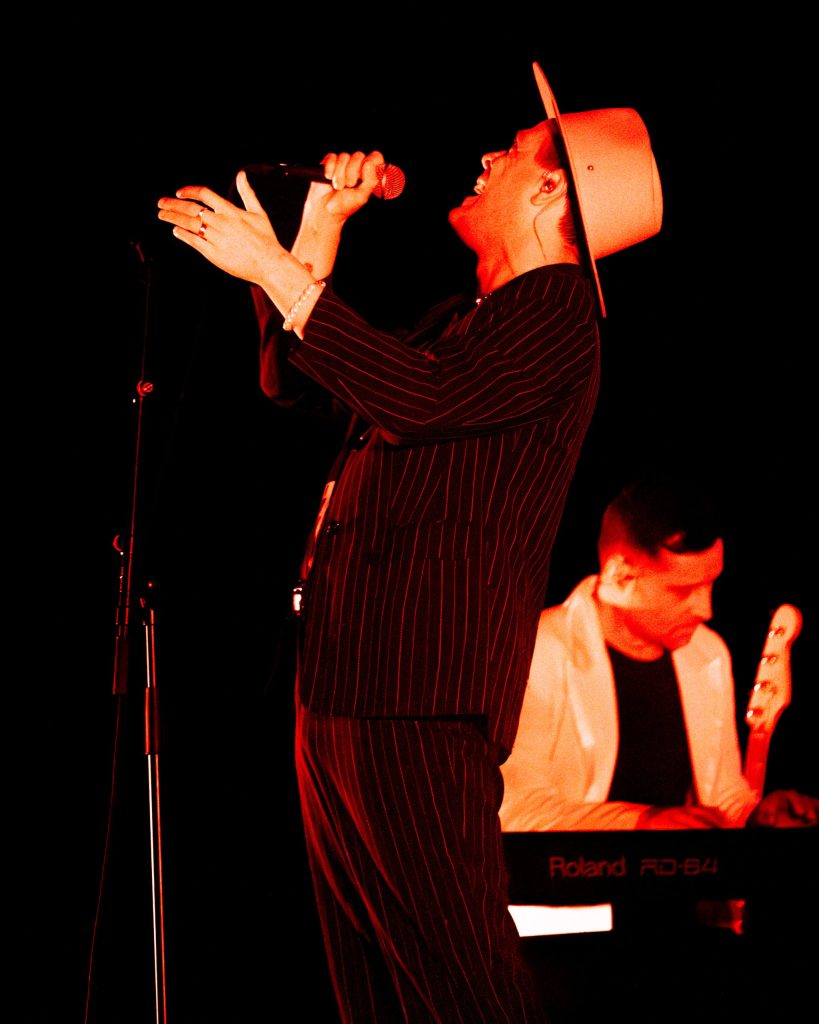 Vocalista dos Fingertips em luz vermelha intensa.