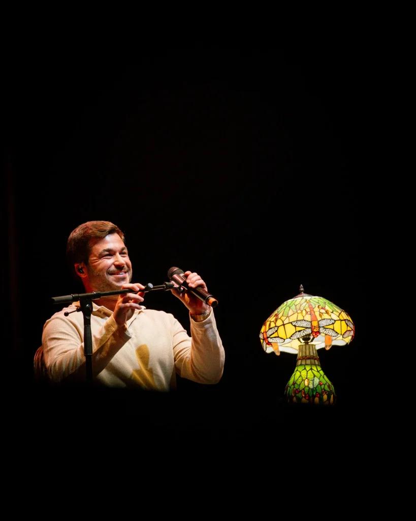 Luís Trigacheiro a sorrir enquanto canta, no concerto no Quartel das Artes em 2025 — fotografia por xpectrum.