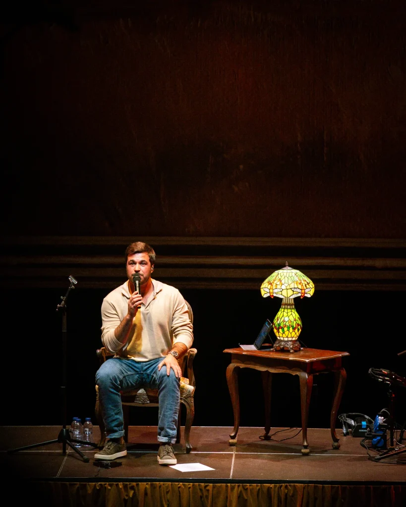 Luís Trigacheiro sentado numa cadeira a cantar, no palco do Quartel das Artes em 2025 — xpectrum fotografia de concertos.