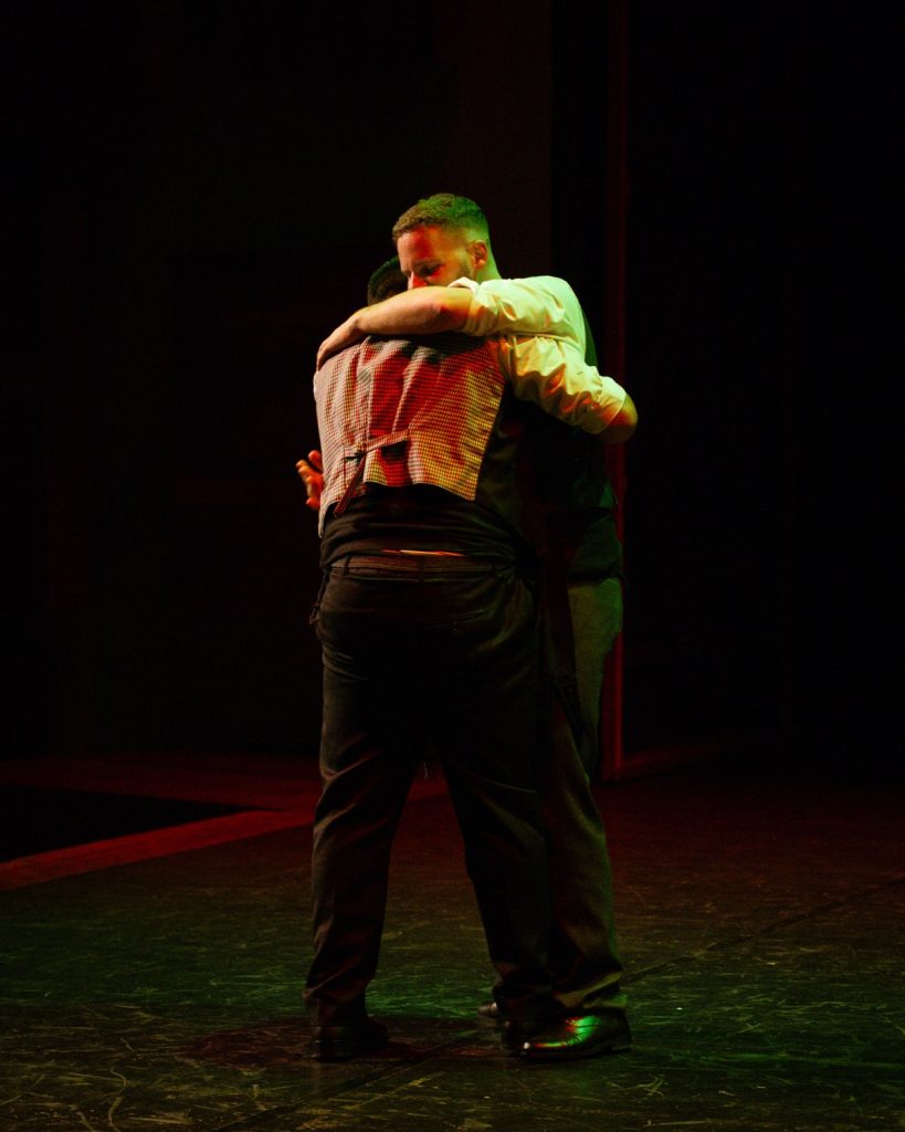 Dois bailarinos masculinos de rancho folclórico em pose de dança no palco escuro do Quartel das Artes durante o evento MOB 2025