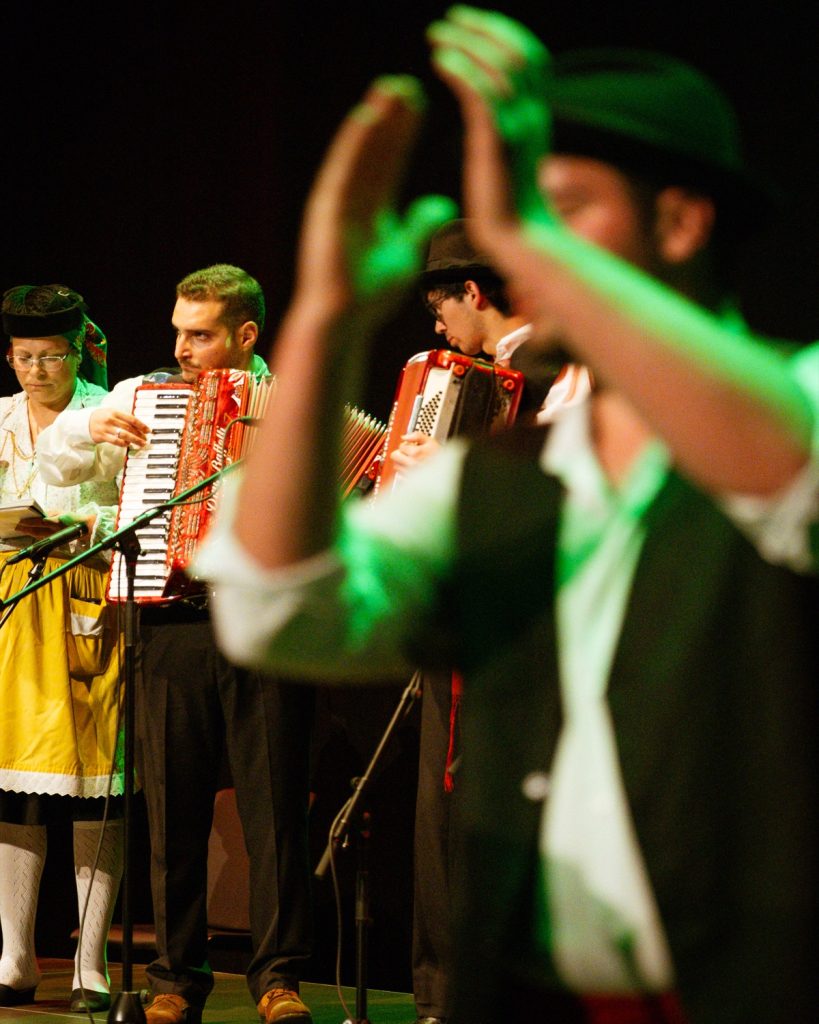 Músicos acordeonistas de rancho folclórico em trajes tradicionais a tocar no palco do Quartel das Artes durante o evento MOB 2025