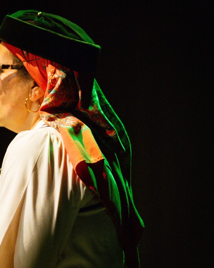Retrato de perfil de mulher em traje folclórico tradicional português com chapéu verde e lenço floral vermelho no evento MOB 2025 no Quartel das Artes