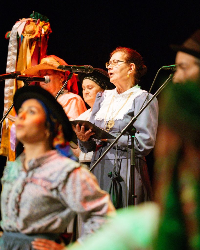 Vocalistas de rancho folclórico em trajes tradicionais portugueses a cantar ao microfone no evento MOB 2025 no Quartel das Artes