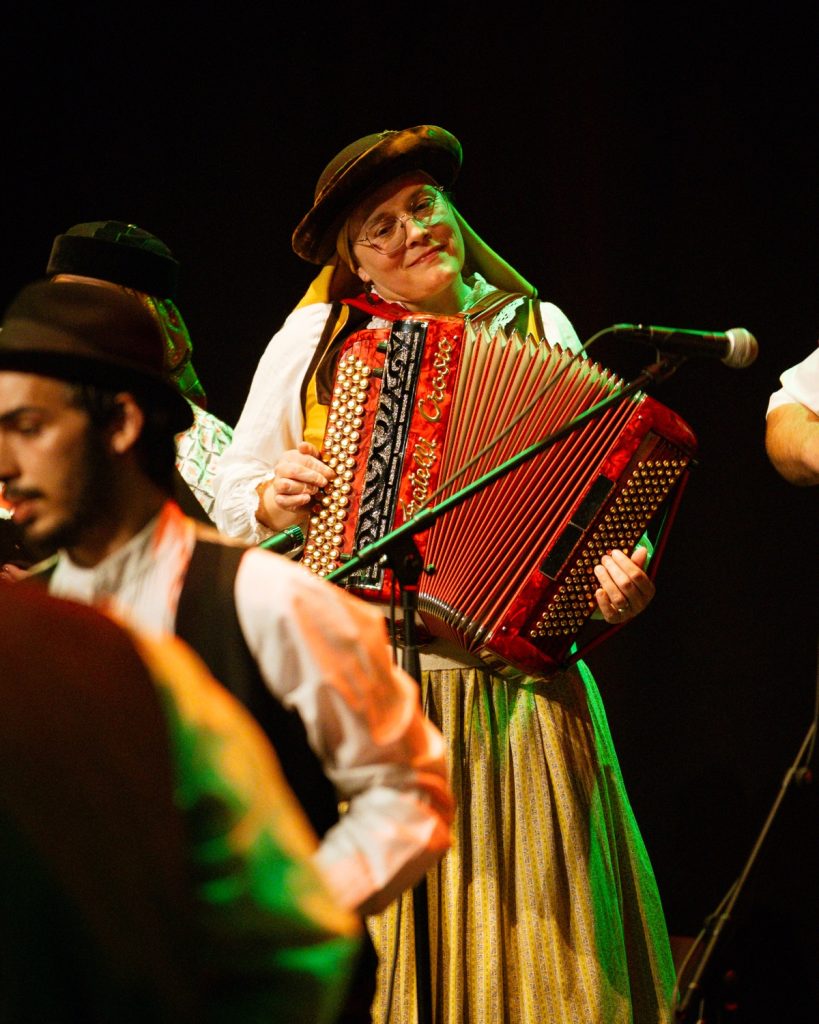 Músico acordeonista em traje folclórico tradicional português a tocar acordeão vermelho no evento MOB 2025 no Quartel das Artes