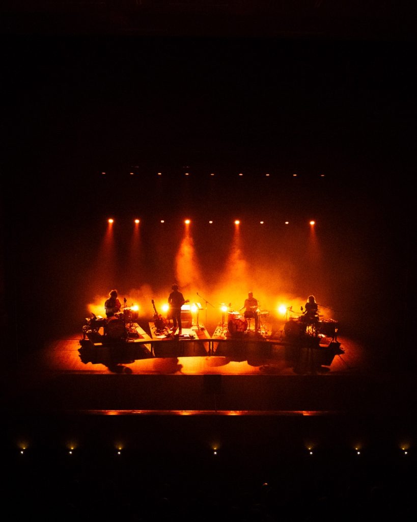 Sangue Suor no Quartel das Artes 2025 – vista geral do palco com toda a banda em silhueta âmbar – fotografia de concertos xpectrum