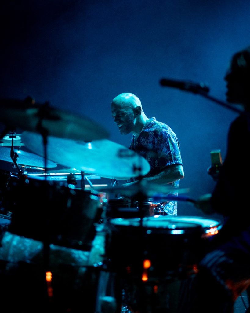 Sangue Suor ao vivo no Quartel das Artes 2025 – baterista em close-up com luz azul fria – fotografia de concertos xpectrum