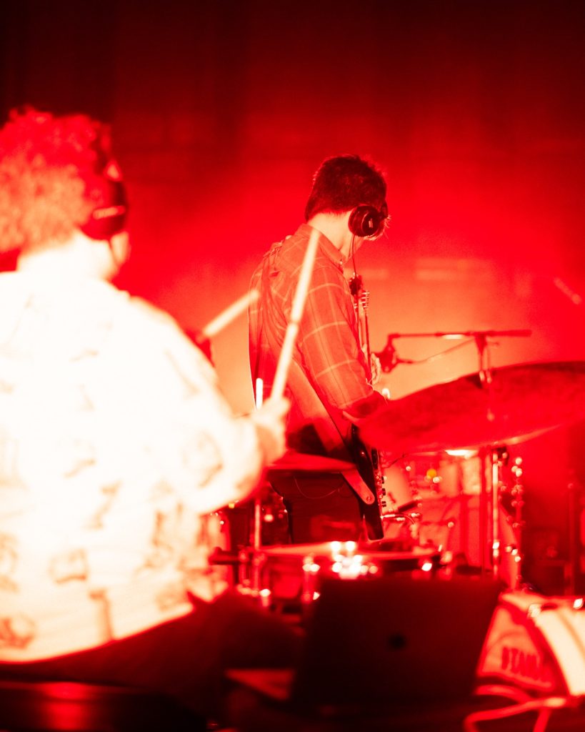 Sangue Suor no Quartel das Artes 2025 – percussão e guitarra em luz vermelha intensa – fotografia de concertos xpectrum