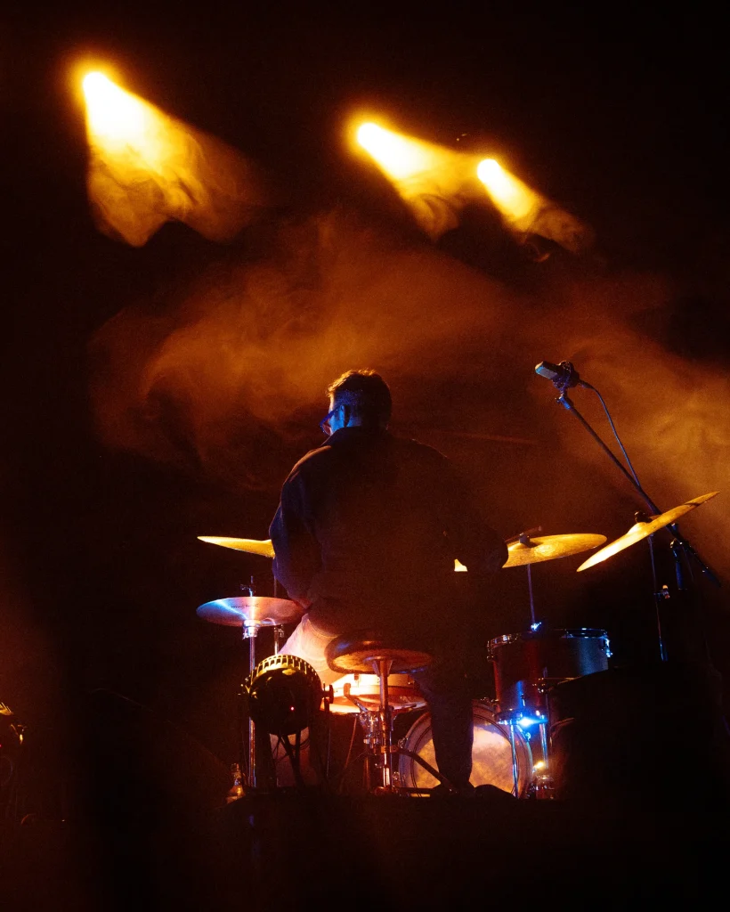 Baterista da banda Solaris em silhueta de costas na bateria, contraluz quente com fumo de palco, Quartel das Artes 2025 — xpectrum fotografia