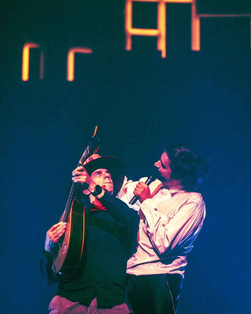 António Bastos ergue viola portuguesa enquanto canta junto a outro músico no palco do Quartel das Artes em 2026