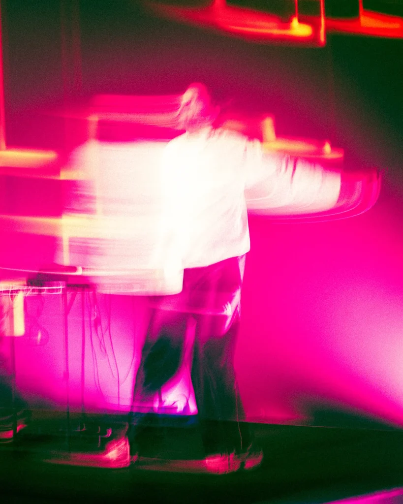 António Bastos captado em movimento sob luz rosa intensa em momento experimental do concerto no Quartel das Artes