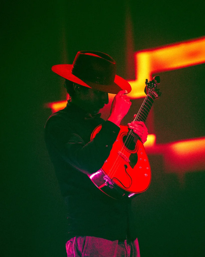 Guitarrista com chapéu e camisa preta toca viola portuguesa vermelha em concerto no Quartel das Artes em 2026