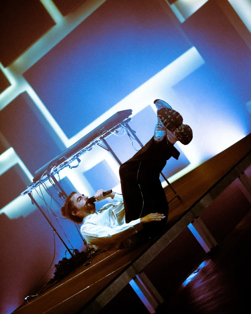 António Bastos em performance teatral sobre o teclado no palco azul do Quartel das Artes durante concerto em 2026
