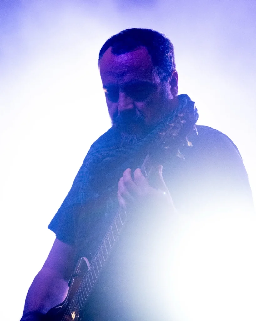 Guitarrista dos Avesso envolvido em fumo e luz violeta a tocar guitarra elétrica no Quartel das Artes em 2025, fotografia de concertos xpectrum.