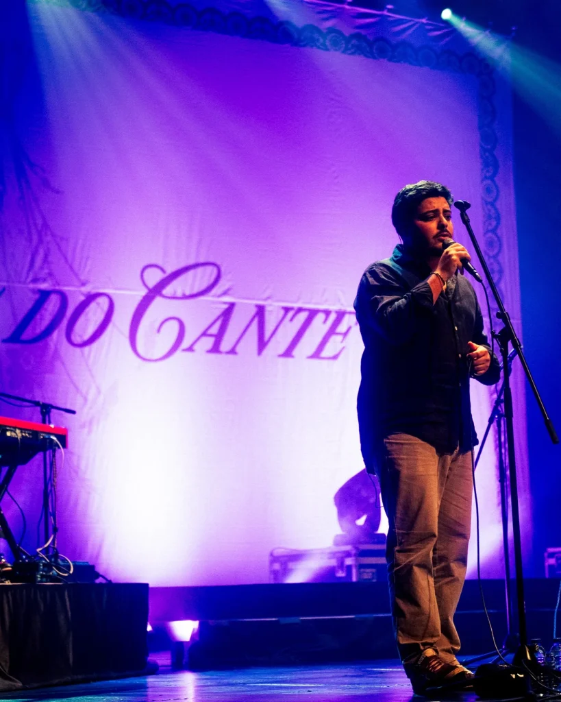 Vocalista dos Bandidos do Cante ao microfone diante do cenário com o nome da banda iluminado a roxo no Quartel das Artes em 2025, fotografia de concertos por xpectrum.