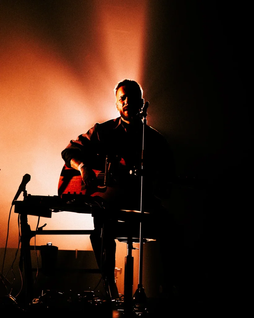 Diogo Piçarra sentado em silhueta com guitarra acústica no Soam as Guitarras 2026, Quartel das Artes