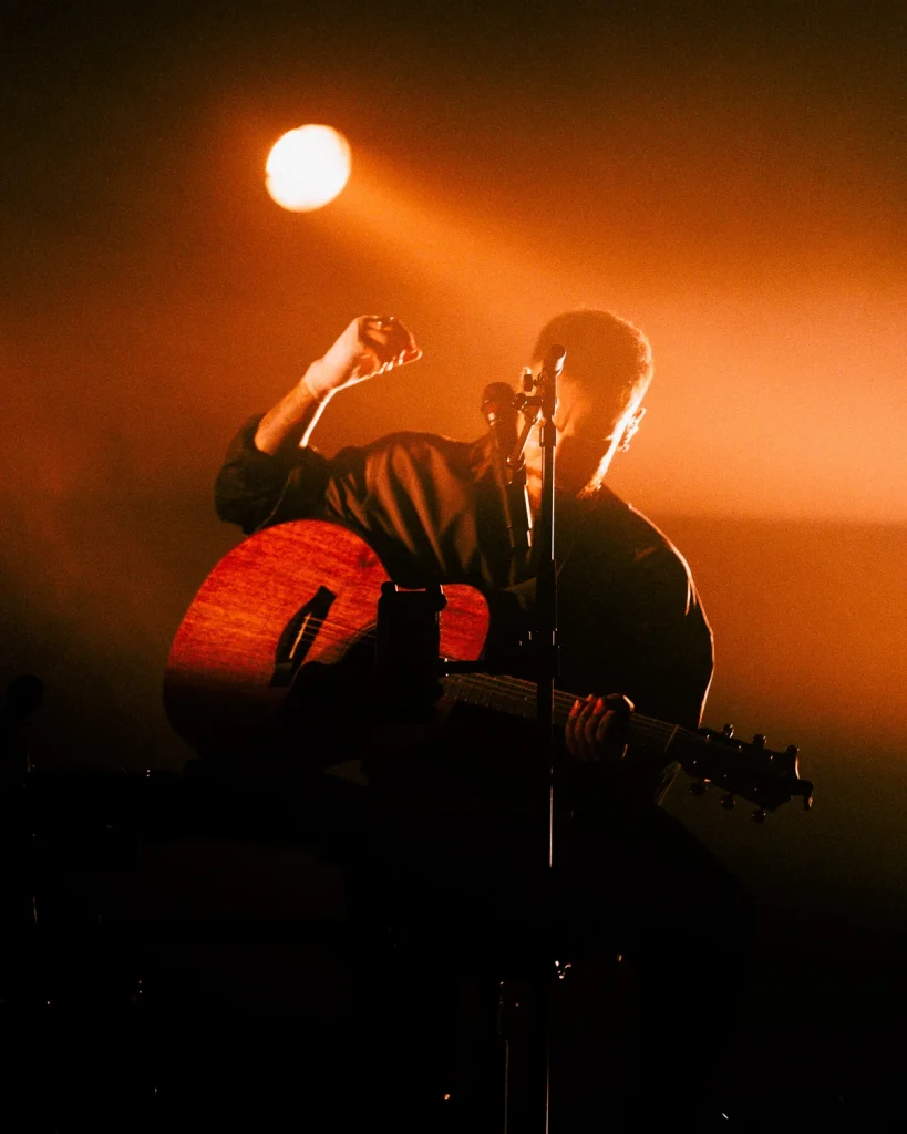 Diogo Piçarra com a mão erguida a tocar guitarra sob spot no Soam as Guitarras 2026, Quartel das Artes