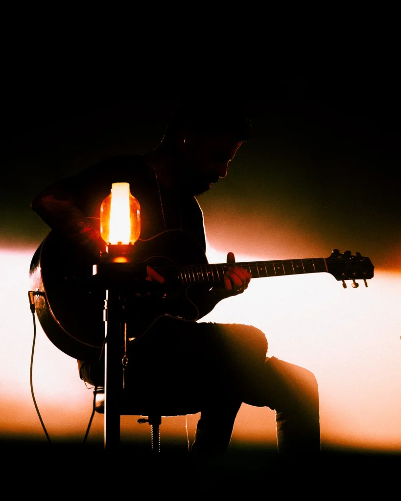 Guitarrista a tocar guitarra junto a candeeiro vintage no Soam as Guitarras 2026, Quartel das Artes