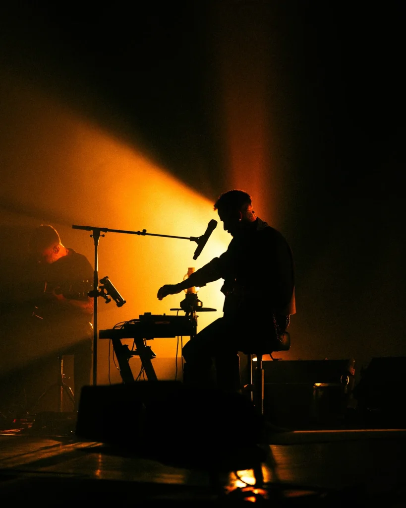 Diogo Piçarra em silhueta no palco com músico ao fundo no Soam as Guitarras 2026, Quartel das Artes