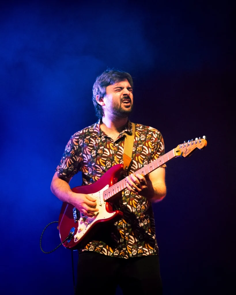 Guitarrista dos Duque Província de camisa estampada a tocar sob luz azul e fumo no Quartel das Artes em 2025, fotografia de concertos xpectrum.