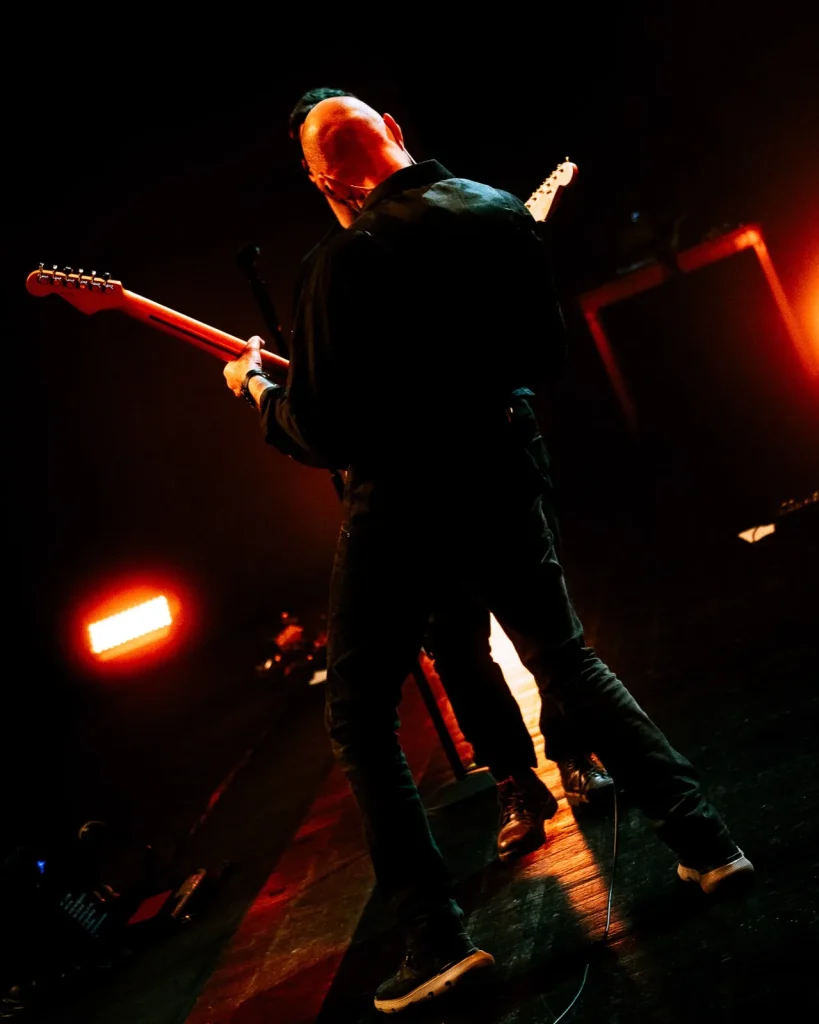 Guitarrista dos Tributus de costas em pose dramática sob luzes de palco — tributo a Pink Floyd no Quartel das Artes