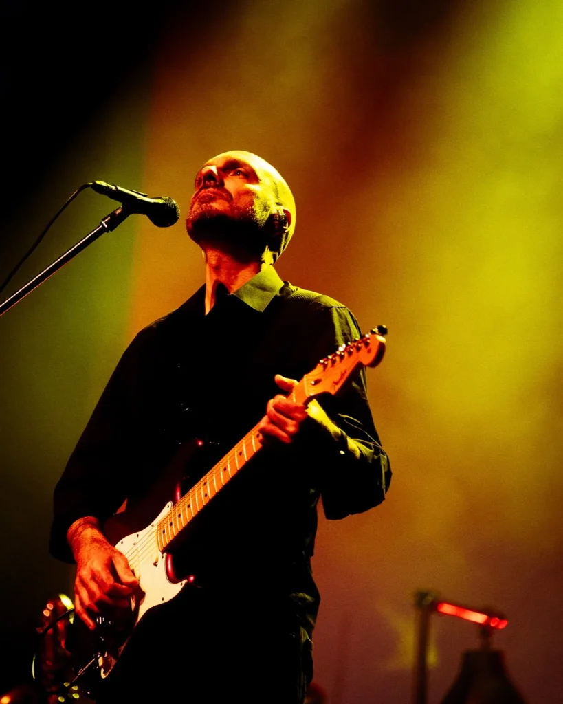 Guitarrista dos Tributus a olhar para cima com Stratocaster sob luz amarela — tributo a Pink Floyd no Quartel das Artes
