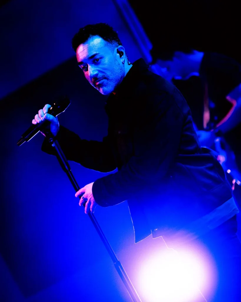 Vocalista dos Tributus ao microfone banhado em luz azul — concerto tributo a Pink Floyd no Quartel das Artes, 2025