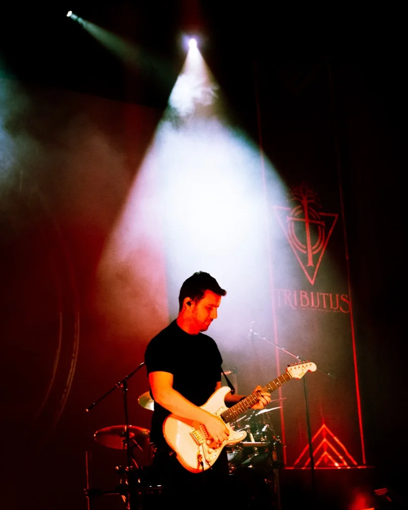 Guitarrista solo dos Tributus em palco vermelho com logo da banda — tributo a Pink Floyd no Quartel das Artes, 2025